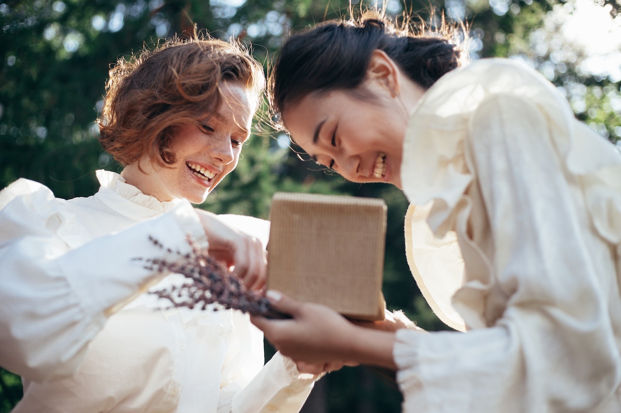 Two ladies in white blouses looking at open gift box